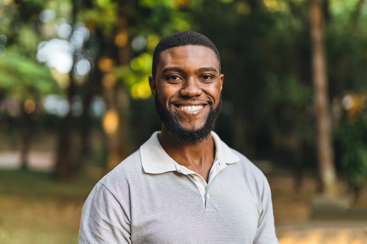 Young man smiling in a public park.