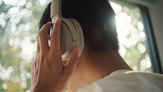 Rear view of a man putting no headphones.