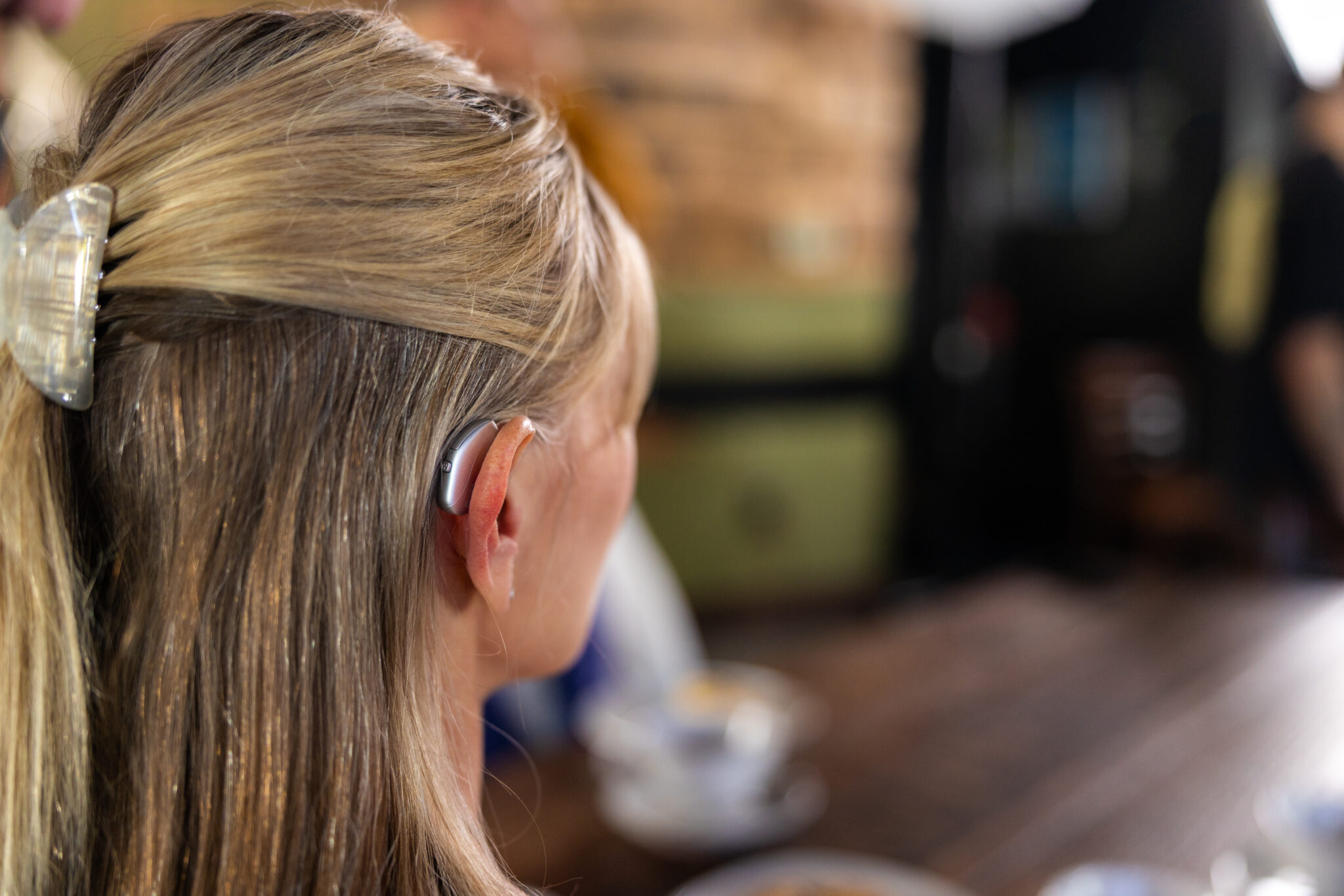 Rear view of a woman wearing a behind-the-ear hearing aid.